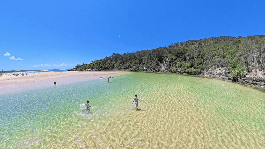 Families swimming in the shallow, clear water at Hat Head Inlet, Mid North Coast NSW