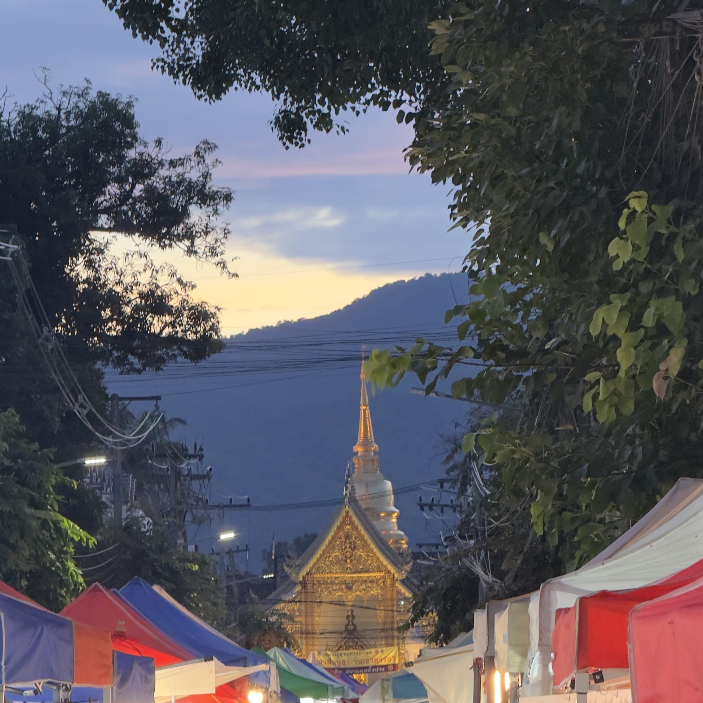 Chiang Mai Night Bazaar Thailand with colourful market stalls and a golden Thai temple illuminated at dusk in the mountains of northern Thailand