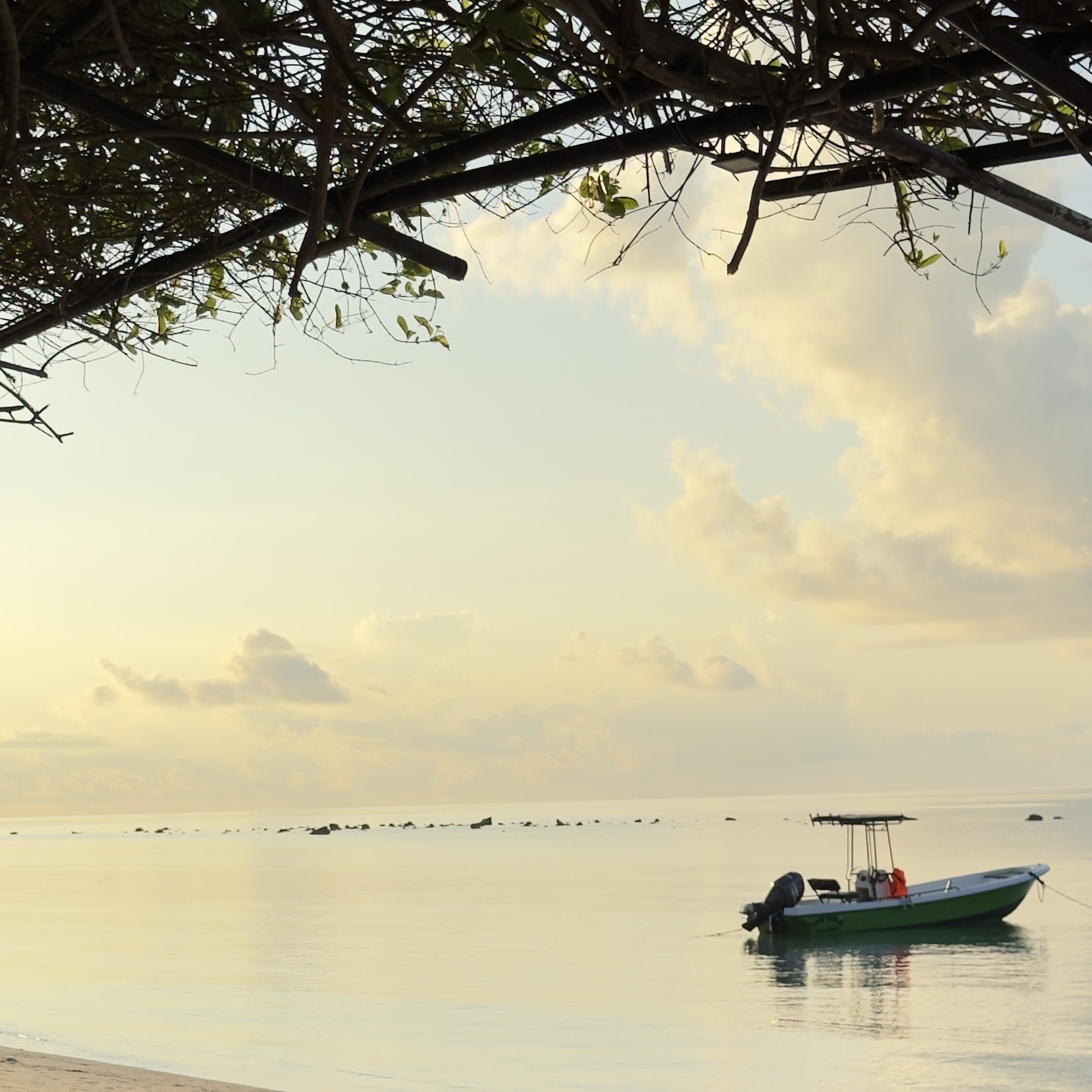 Khao Lak With Kids: Where To Stay, Eat & Best Things To Do Khao Lak beach Thailand with a traditional longtail boat floating on calm water at sunset along the Andaman coast