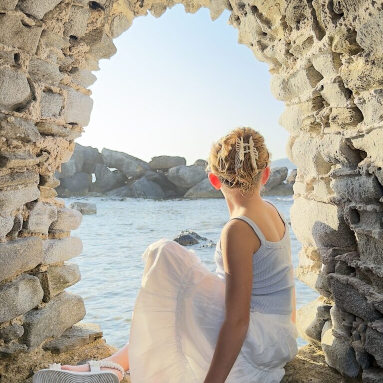 View from stone arch in Paros Greece with girl looking out over Aegean Sea
