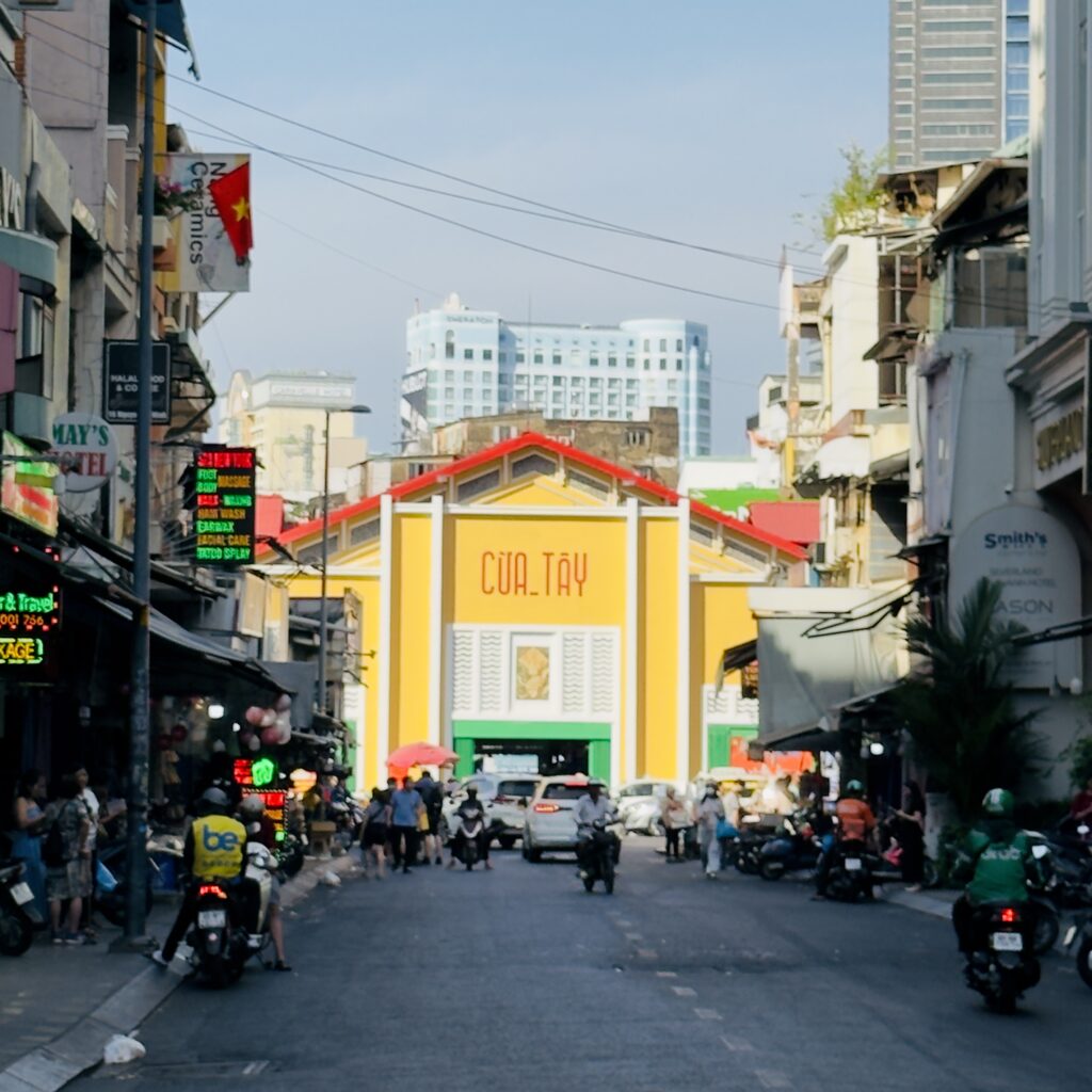 Ben Thanh Market in Ho Chi Minh City Vietnam with its distinctive yellow facade, busy street and motorbikes