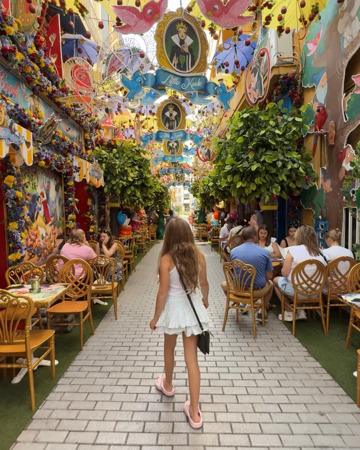 Little Kook in Athens, Greece, a colourful themed cafe with whimsical murals, hanging decorations, lush greenery and outdoor dining seating