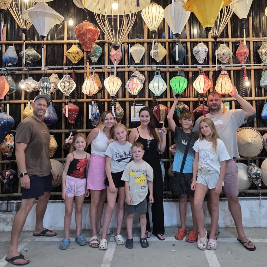 Family group posing in front of colourful handmade lanterns during a lantern-making class in Hoi An, Vietnam