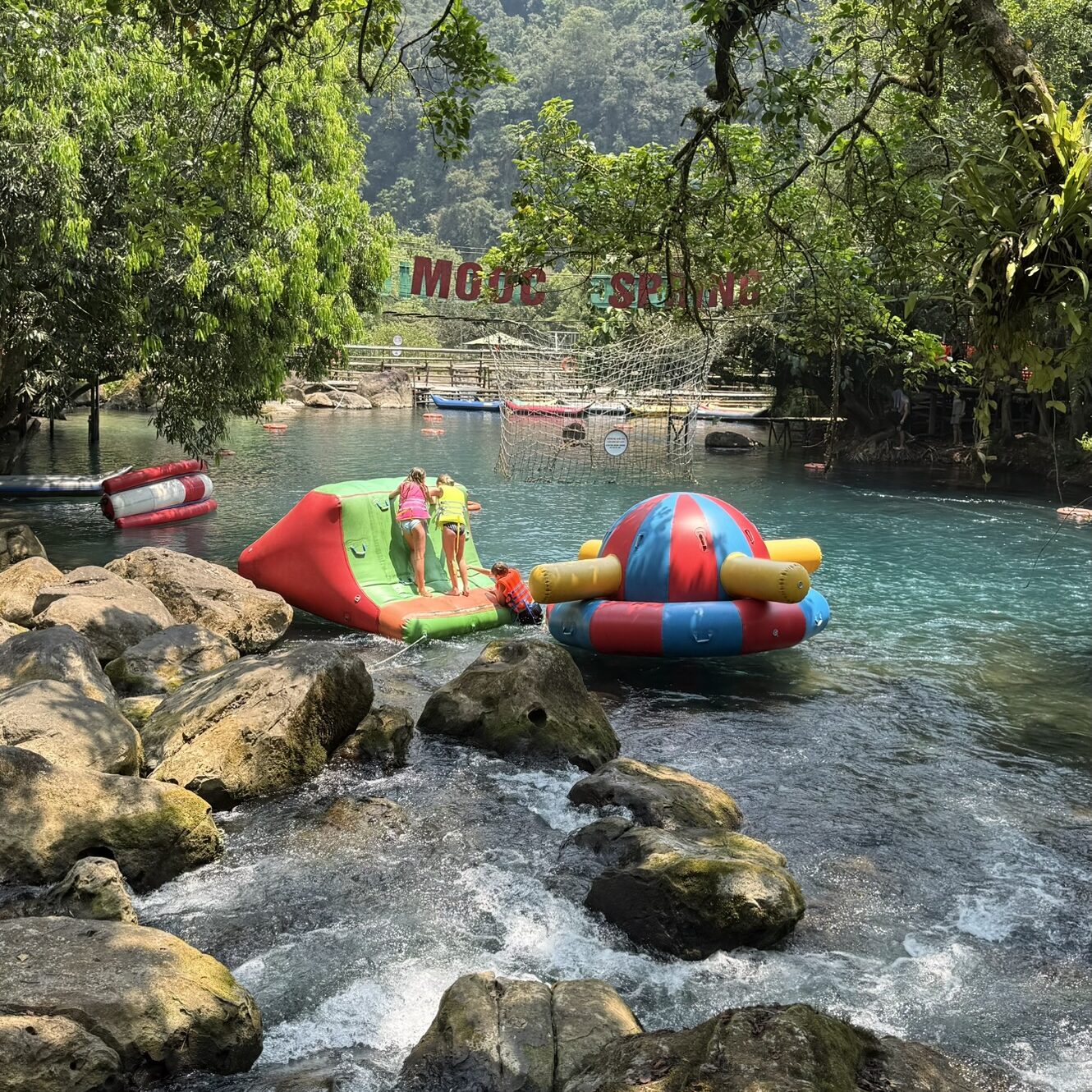 Phong Nha With Kids: Where To Stay, Eat & The Best Things To Do Family enjoying inflatable water activities at Mooc Spring, Phong Nha, Vietnam