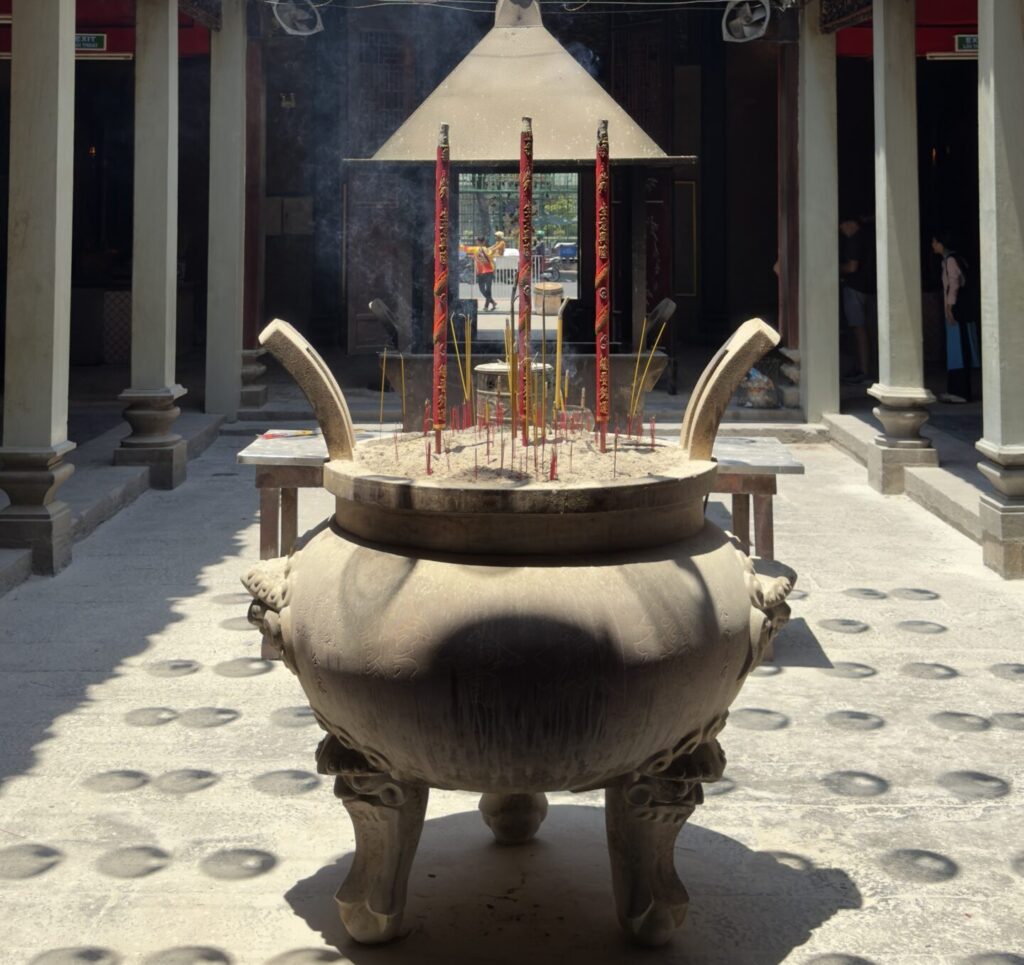 Chinese temple in Ho Chi Minh City Vietnam with a large incense burner filled with burning incense sticks in the courtyard