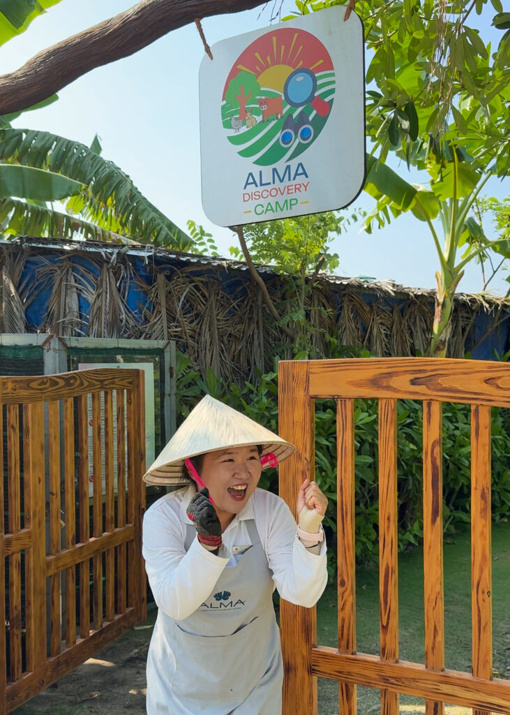 Alma Resort farm experience in Vietnam with an adult farmer wearing a traditional Vietnamese conical hat while demonstrating local farming activities