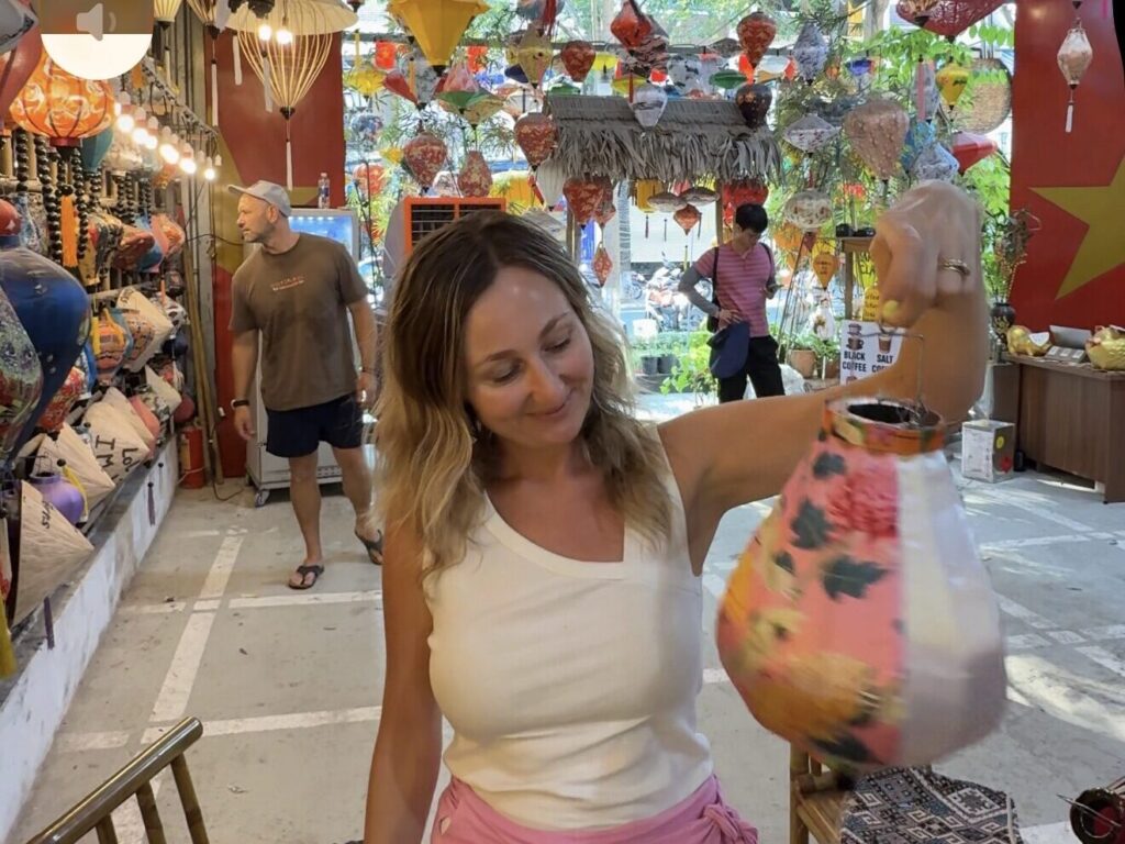 Women holding a colourful watermelon-shaped lantern at a traditional lantern shop in Hoi An, Vientmam